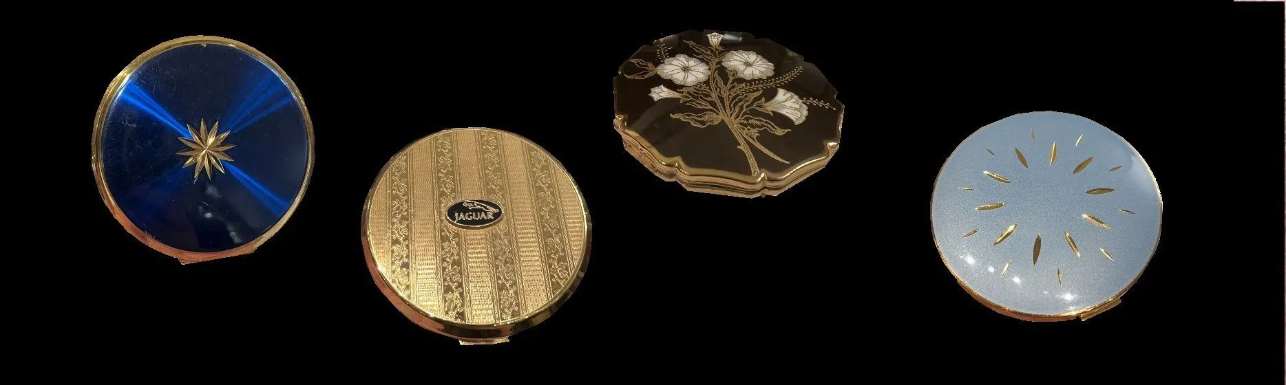 Four antique powder compacts with various designs.